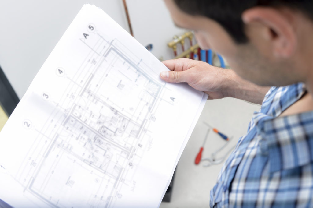 A person reviews a large architectural blueprint, holding the drawing up for closer inspection.