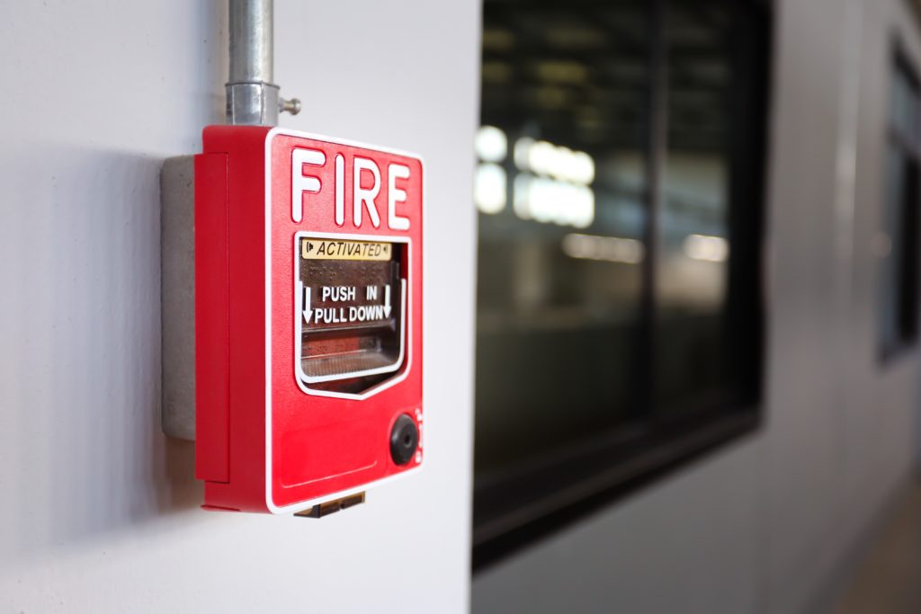 A red fire alarm pull station mounted on a wall in factory.